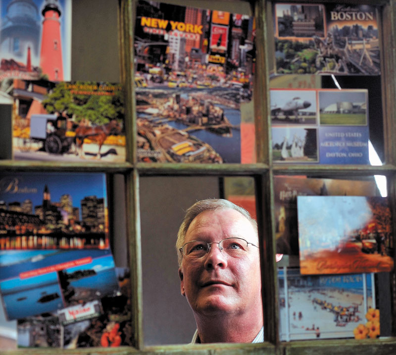 FROM ALL OVER: Bob Woodsome looks at a collection of postcards mailed to Sonny's Pizza on Main Street in Fairfield from an unknown patron.