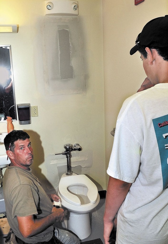 BREAK AND ENTRY: Richard Prentiss, left, and his son Ryan repair two holes in a bathroom wall on Tuesday after thieves broke into Rafting Randy's Whitewater Supply business in downtown Skowhegan earlier. The thieves broke a gate and sawed through two doors to gain entry and stole $3,000 worth of merchandise and cash.