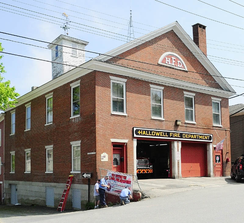 Hallowell volunteer firefighters hang a banner Thursday at the fire station.