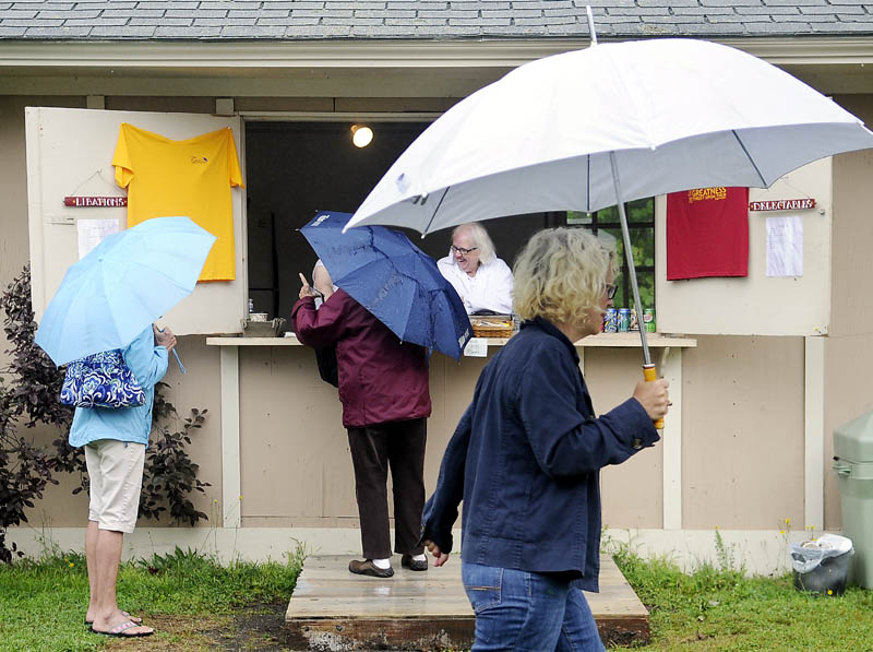 Customers line up with umbrellas at a concession stand Wednesday at Cumston Hall before a showing of “Much Ado About Nothing” by the Theater at Monmouth. People planning to attend a performance Thursday may want to pack an umbrella for a matinee of “James and the Giant Peach” but, with sun expected in the late afternoon, leave it home for the evening showing of “Blithe Spirit.”