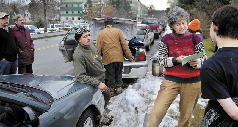 PERMIT TO ASSEMBLE: Occupy Augusta movement member Diane Messer, second from right, inspects a permit Monday she was directed to fill out by Capitol Police for an application to protest in Capitol Park in Augusta. A federal district court judge issued an order Monday that will allow protesters to remain in the park for at least another week.