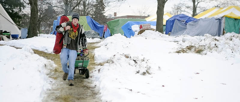 DECAMPING? Nic Messier, of Hallowell, carries camping gear out of the Occupy Augusta encampment in Capitol Park on Saturday afternoon.