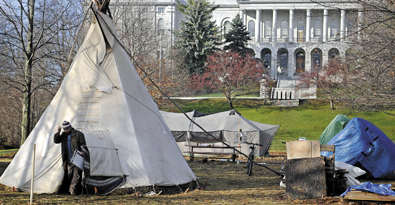 RISE AND SHINE: An Occupy Augusta movement member emerges from a teepee Wednesday morning at Capitol Park in Augusta. Approximately six people slept overnight in the park in tents and a teepee while the future of the protest will be determined in federal court.