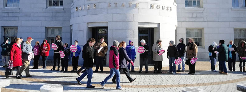 Protetsters ring the State House on Saturday afternoon in Augusta as part of the annual "Hands Around the Capitol Rally and March."