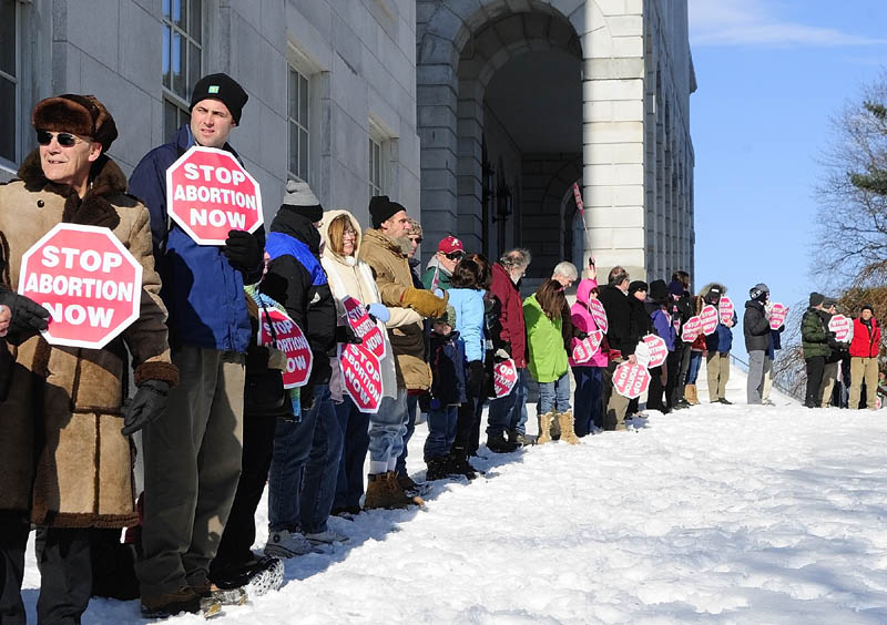 Protetsters ring the State House on Saturday afternoon in Augusta as part of the annual "Hands Around the Capitol Rally and March."