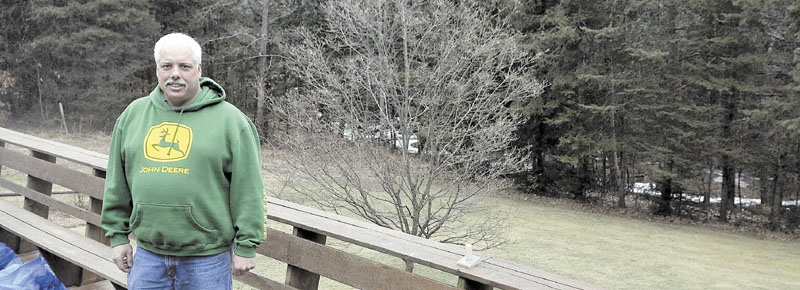 Rocky Gravel stands on the back deck of his Shorey Road residence in Winslow with a little brook in the back ground. According to FEMA, that brook put him in a floodplain. It cost him $2,000 to prove otherwise.