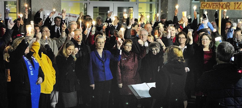 The Rev. Jill Saxby, executive director the Maine Council of Churches, center at podium, speaks during a candlelight vigil outside the State House before Gov. Paul LePage's first State ofthe State address on Tuesday night in Augusta.