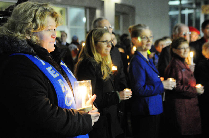 The Rev. Carie Johnsen, the minister of Unitarian Universalist Community Church of Augusta, far left, holds a candle at a vigil outside the State House before Gov. Paul LePage's first State of The State address on Tuesday night in Augusta.