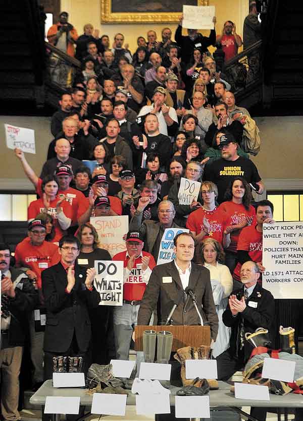 SPEAKING UP: Supporters cheer after Matt Schlobohm, the executive director of the Maine AFL-CIO, finishes up a rally for Labor Lobby Day in the State House in Augusta. Union members had lobbied legislators earlier in the day before the noon rally Thursday. The shoes on the table were props for the “walk in our shoes” theme of the rally.