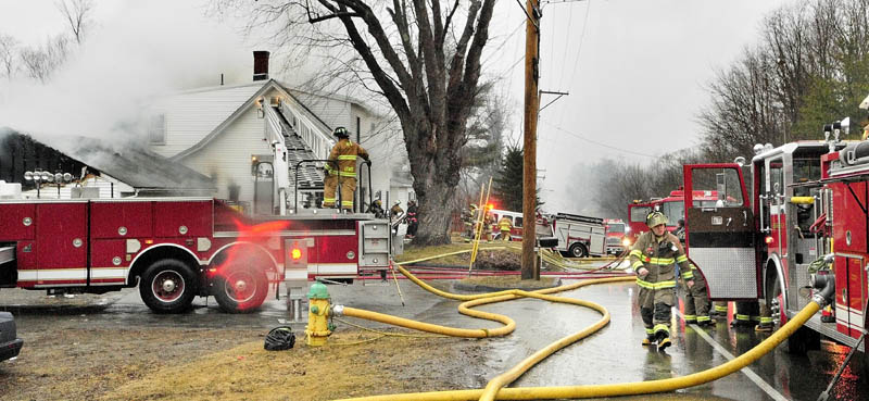 Firefighters work at the scene of a fire in a four-unit apartment building at 208 Hospital Street in Augusta this afternoon. Winthrop, Chelsea and Togus fire departments also responded to the blaze that heavily damaged portions of the building.