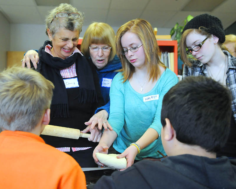 Chris Walen, 62, left, and Nancy Leavitt, 73, roll cookie dough with Maranacook Community Middle School seventh graders Callyn Harger, right, and Ashley Bryant during a meeting of the new Senior Center at the Readfield school.