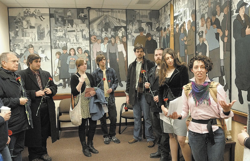 Jessica Graham, right, leads a gathering last year in front of a mural honoring labor, in the Department of Labor building’s lobby in Augusta.