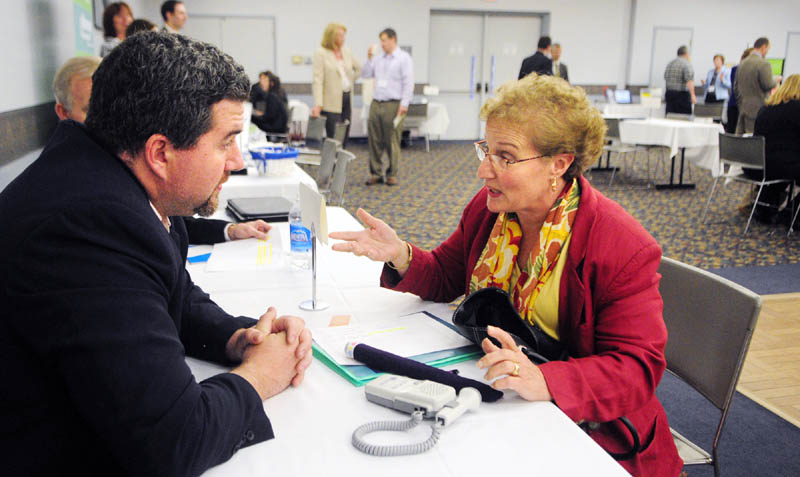 Bradley Galley, of Machias Savings Bank, left listens as Janet Eugley explains how the device she designed can help pregnant women more easily hear the heartbeat of their babies at the U.S. Small Business Administration-organized Meet the Lenders Speed Banking Conference on Wednesday at the Augusta Civic Center.