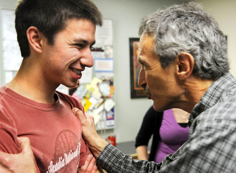 Maranacook Community High School physics teacher Steve DeAngelis, right, congratulates student Jared Diou-Cass on receiving a $100,000 scholarship Monday at the Readfield school. Diou-Cass will receive the money from Proton OnSite, a Connecticut clean energy company.