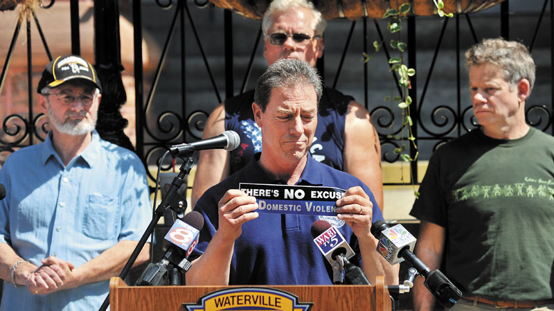 Waterville City Manager Mike Roy holds a bumper sticker that reads “There’s No Excuse for Domestic Violence” as he speaks on the subject of domestic violence during a rally last June to call on men to take responsibility for creating a community free of domestic violence.