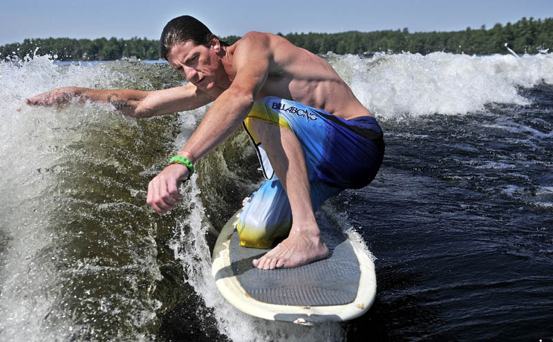 Staff Photo by Michael G. Seamans Troy Welch,of waterville, surfs the boat wake on Messalonskee Lake in Oakland Friday morning. Welch was towed behind the boat until the proper speed was achieved allowing Welch to to ride the make like a surfer rides a wave in the ocean.