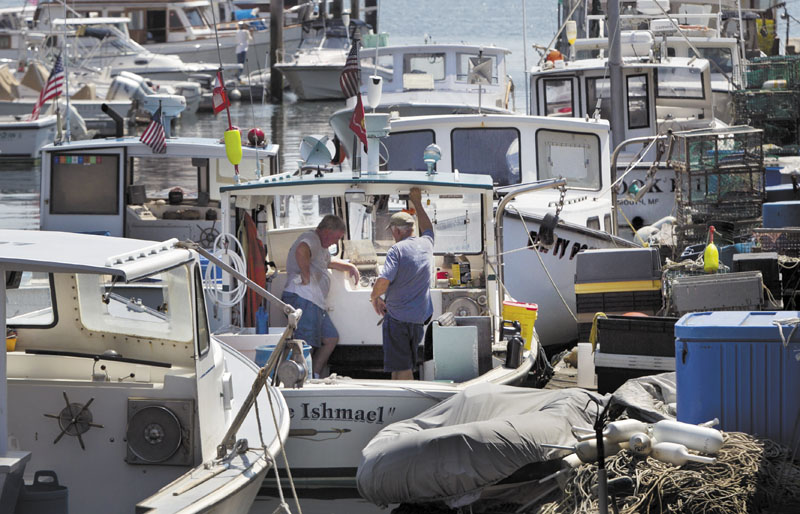 Lobstermen take a break while doing maintenance work, Thursday in Portland, Maine. Plentiful lobsters this season has depressed the prices that lobstermen have been getting, to below $3 a pound. In recent weeks Maine lobstermen stayed off the water for several days to try to let the market rebound. (AP Photo/Robert F. Bukaty)