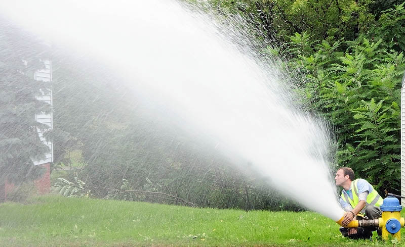 Adrian Beaudoin, of the Winthrop Utilities District, aims the blasts of water coming from a hydrant on Wednesday morning in downtown Winthrop. He said that it was part of the district's annual flushing of their water lines.