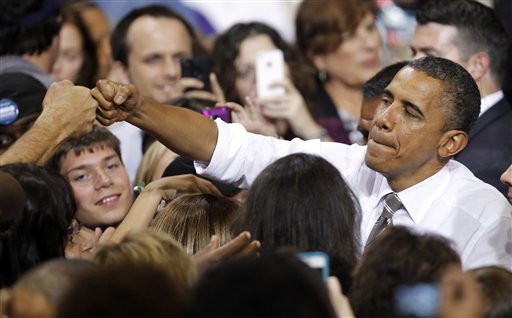 FILE - In this Sept. 26, 2012 file photo, President Barack Obama pounds fists with a supporter after speaking at Kent State University in Kent, Ohio. Mitt Romney�s campaign is working hard to chip away at President Barack Obama�s advantage among early voters, and there are signs the effort is paying off in North Carolina and Florida, two competitive states that the Republican nominee can ill afford to lose. Obama is doing better in Iowa, another battleground state important to both candidates. (AP Photo/Tony Dejak, File)