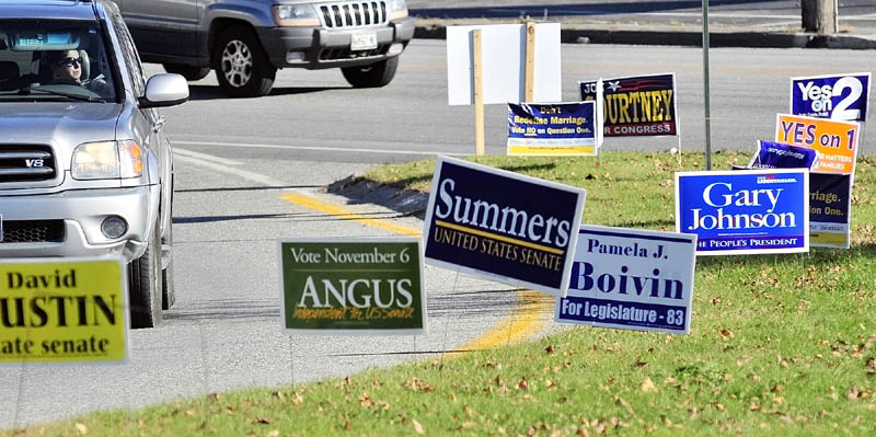 A driver looks at campaign signs while turning off Western Avenue onto Route 17 on Thursday afternoon, near the Manchester Town Office.