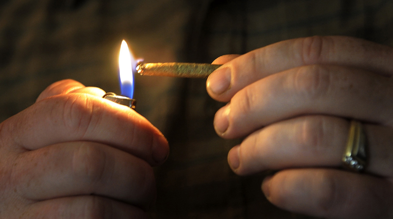 TREATMENT: Glenn Lewis lights a joint in his Manchester home earlier this month. He and his wife Catherine are medical marijuana patients.