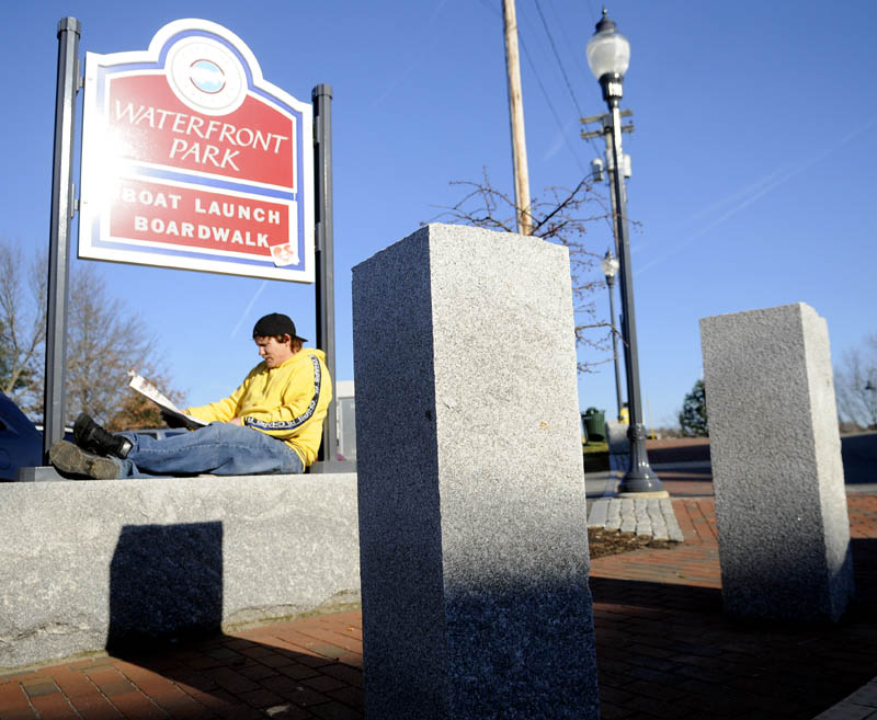 Thomas Blancato reads Tuesday at the entrance of the waterfront park in Gardiner, as temperatures hovered in the mid-50s F. Blancato said he reads outside every day he's not working. "It's a nice spot right here," he said.