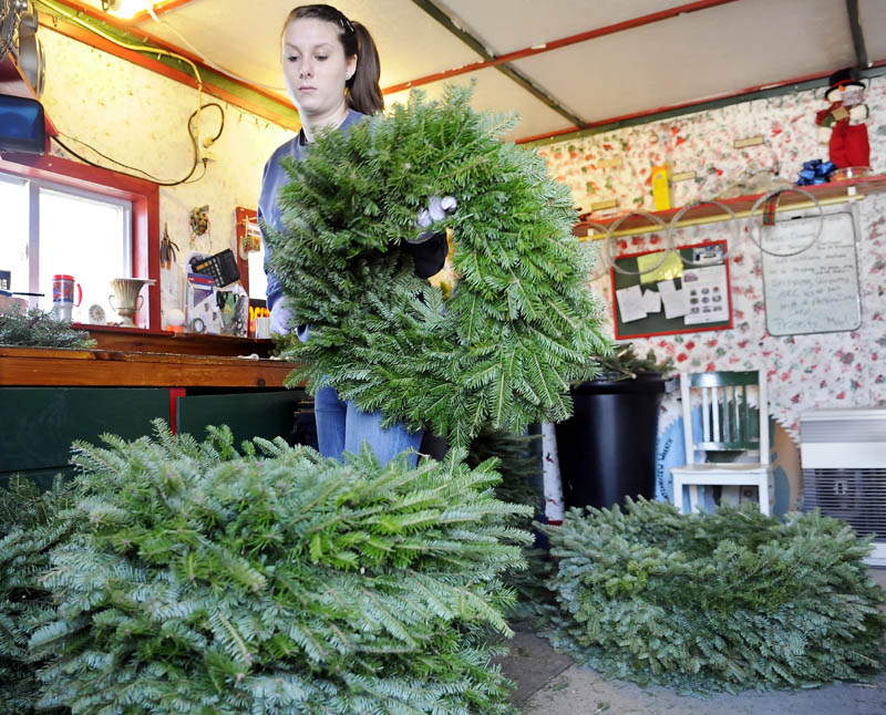 Crystal Gatcomb stacks a wreath she wrapped Monday with her grandmother, Darlene Ames, at the latter's evergreen bough decoration business in Fayette. Mountain View Wreath Shop creates several thousand of the Christmas adornments between November and Christmas, according to Ames.