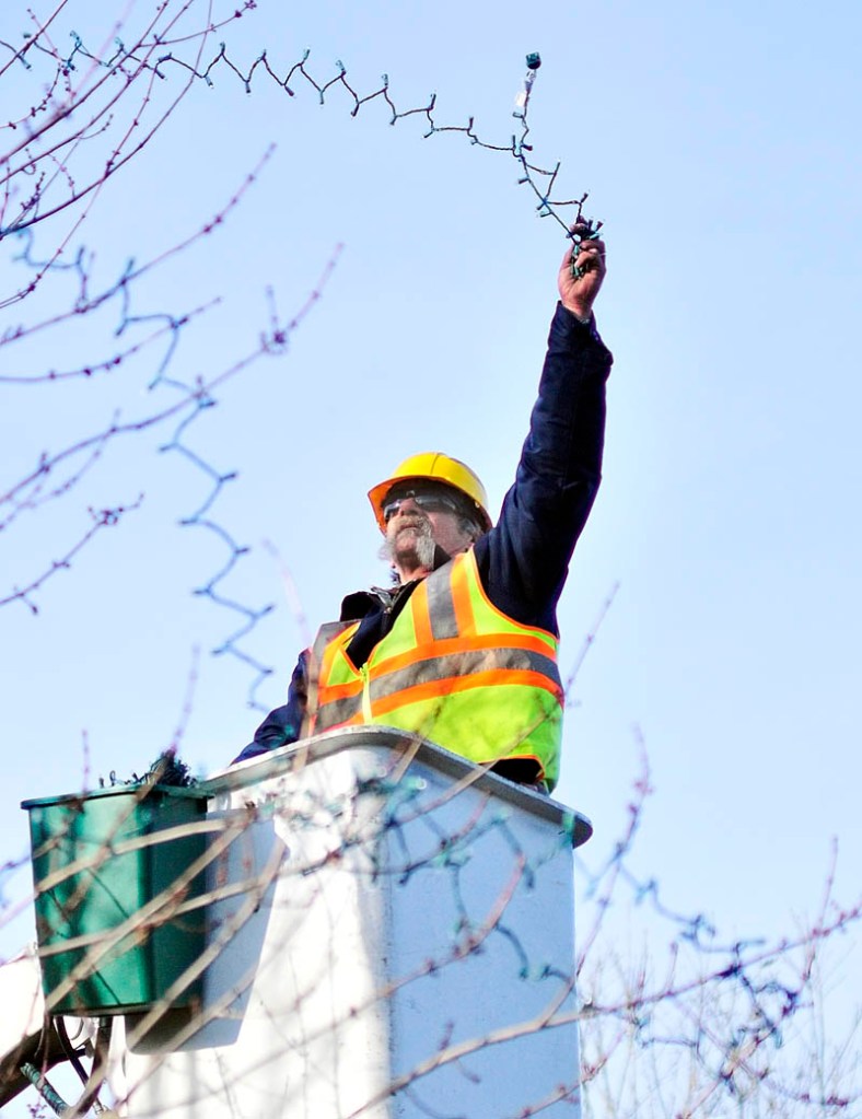 City worker Andy Chavarie strings holiday lights on a tree Thursday afternoon in Augusta Waterfront Park. Chavarie and and a coworker were putting almost 3,000 lights on several trees near the gazebo alongside the Kennebec River.