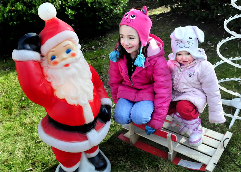 Skyla Dean, left, and her sister, MacKenzie, play on the Christmas decorations their father was setting up on Main Street in Pittsfield on Sunday. "I love Santa and Christmas is my favorite," Skyla said.