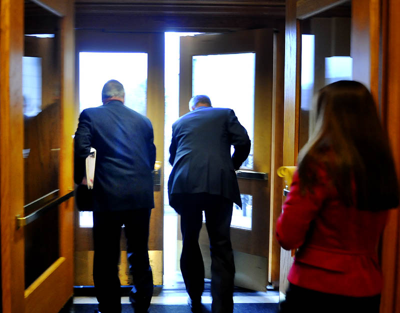 Gov. Paul LePage, left, departs his Augusta office on Tuesday with a state police officer and spokeswoman Adrienne Bennett, right, after declining to speak to the press. Gov. LePage on Tuesday called off his scheduled meeting with incoming Democratic leadership, saying he would not have "that meeting" until Democrats call off a paid "tracker," who follows him with a video camera, according to a prepared statement released by his office.