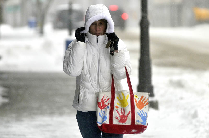 Nancy Karter, of Fairfield, holds her hood as she walks down Main Street in downtown Waterville on Thursday.