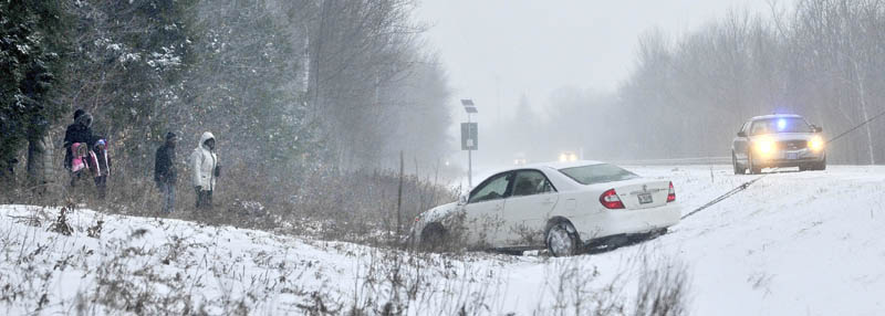 People watch as their car is pulled from the woods on Interstate 95's southbound lanes, just south of Exit 127 near Oakland, on Thursday.