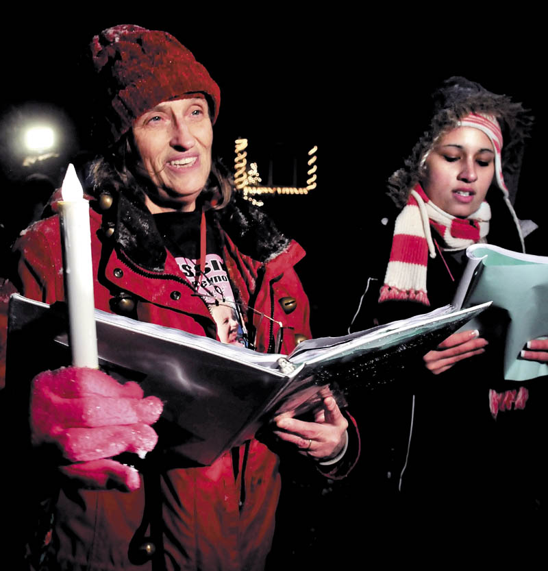 Glenda Armandi, left, and Jessica Verdejo join two dozen other people in singing Christmas carols on Monday outside the home at 29 Violette Ave. in Waterville, where toddler Ayla Reynolds was reported missing one year ago.