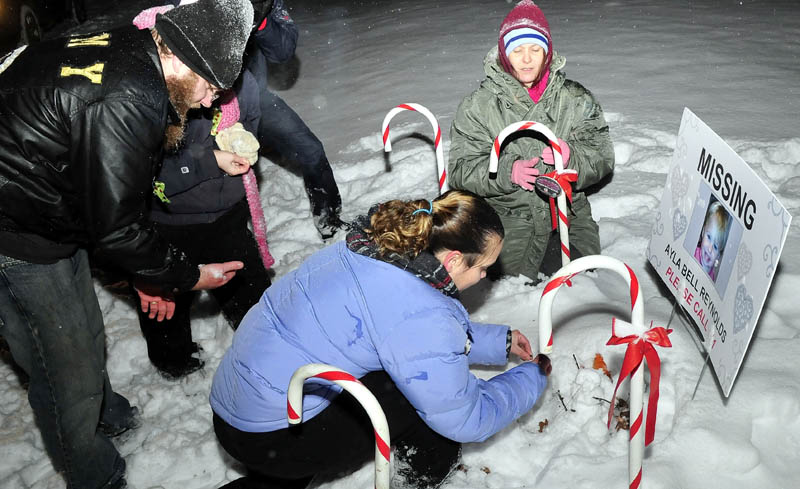 Staff photo by David Leaming REMEMBERED: Vigil organizer Karen Francis and others place candles at the base of a poster with a photo of missing toddler Ayla Reynolds outside the girls home in Waterville on Monday, Dec. 17, 2012. Reynolds was reported missing one-year ago.