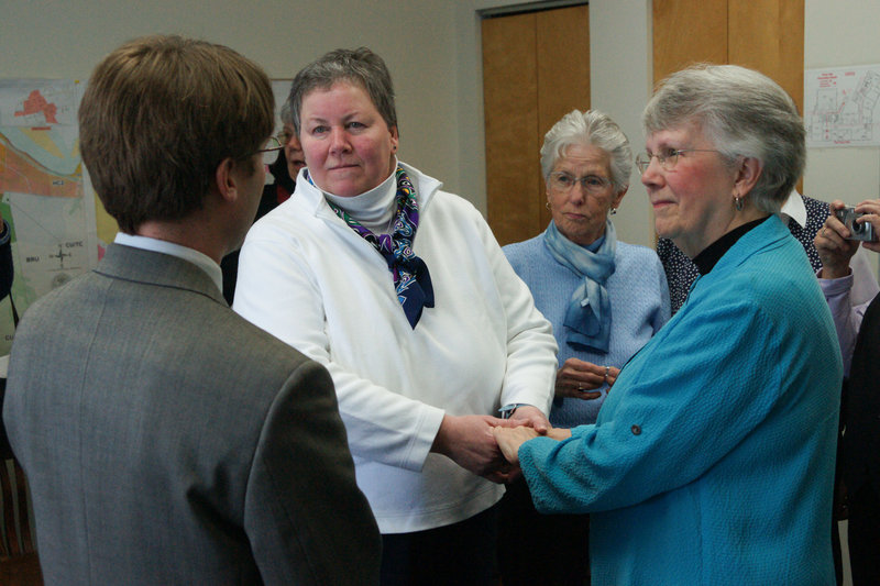 Cathy Meaney, 57, and Anne Merrifield, 73, take marriage vows at Brunswick Town Hall on Saturday. Town Councilor Dan Tucker officiated at the wedding. Their friend Elaine Mower of Brunswick was a witness.