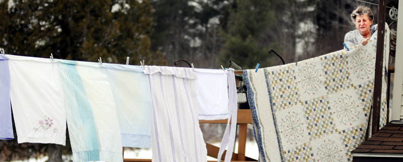 Phyllis Wing collects a bed spread Wednesday from a clothes line outside her Manchester home. Wing said damp weather forced her to bring the spread inside for a turn in the dryer.