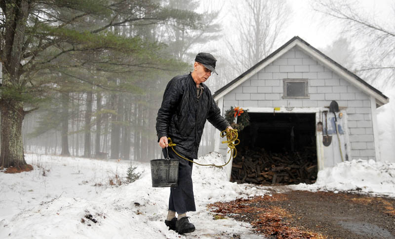 Robert Clark, 74, draws water from the well at his Manchester farmhouse Sunday. Clark said he pulled buckets by hand after the power went out.