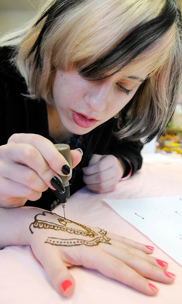 Meryl Kus draws a temporary tattoo on Cassidy Bane's hand on Saturday at the Gardiner Public Library.