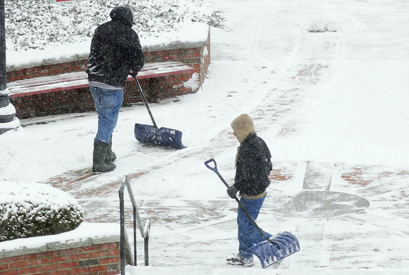 Workers shovel snow on Wednesday in front of Key Plaza in downtown Augusta.