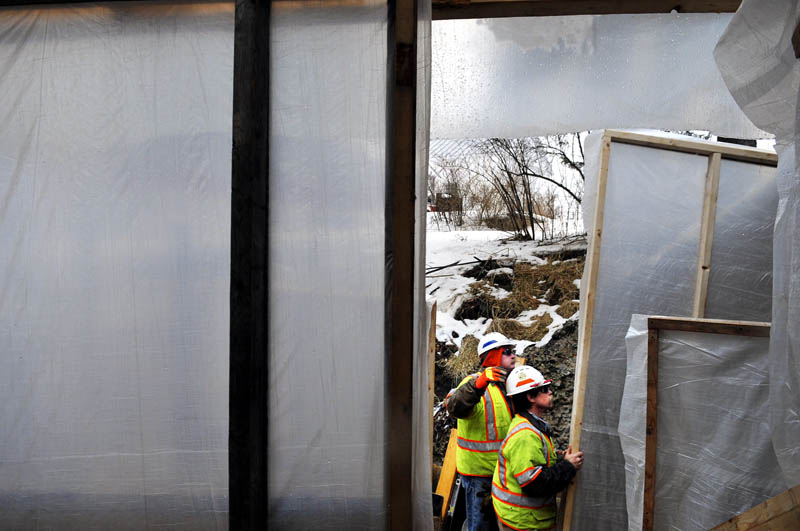 Maine Department of Transportation workers Dave Ferland, left, and Lenny Sioch hang plastic tarp frames with colleagues Tuesday on a platform beneath the bridge on Route 41, spanning Mill Stream in Vienna. The workers were erecting a winter enclosure to commence repairing posts, rails and wing walls on the bridge, according to Ferland, the supervisor. The crew should be finished fixing the span in about six weeks.