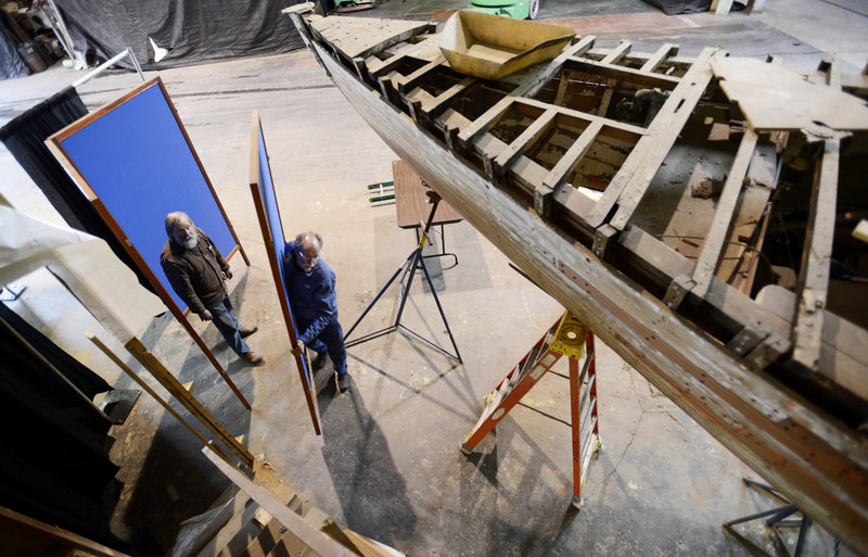 Dave Hackett, head of the woodshop, and Robert Flight, project manager with the Portland Yacht Club, set up an area around a 1926 sailboat that is undergoing restoration at the Yacht Club as they set up for the Maine Boatbuilders Show on Wednesday, March 13, 2013.