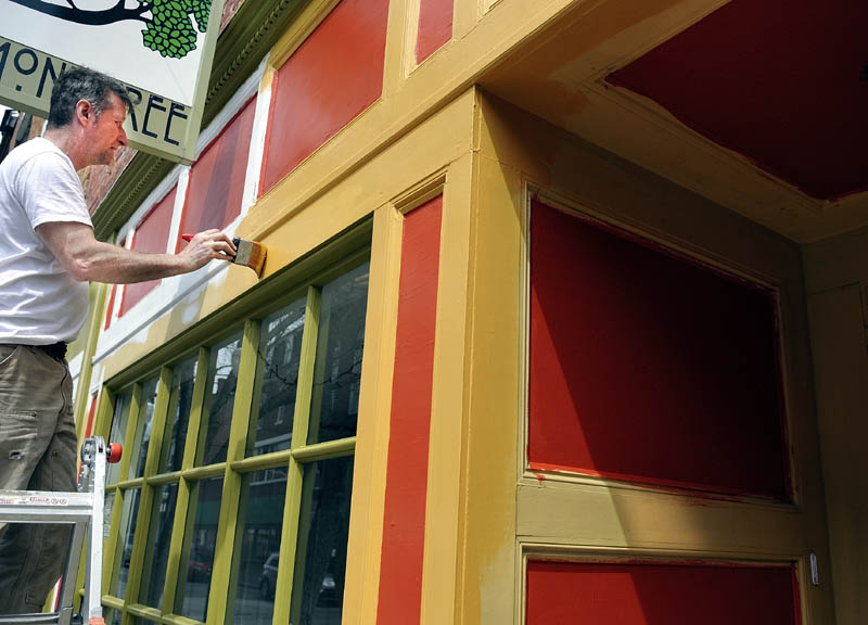 Scott Elliot applies a coat of gold paint Monday on the exterior trim of the Monkitree gallery on Water Street in Gardner. Warmer weather and the imminent arrival of summer tourists has merchants and builders finishing up spring construction work. "Tis the season," Elliot said.