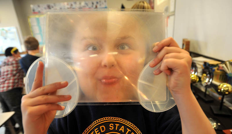 Alexis Bolduc, 10, a fifth grader at Albert S. Hall School in Waterville, inspects a magnifying glass in the physics group during the first Science, Technology, Engineering and Math Day on Friday.