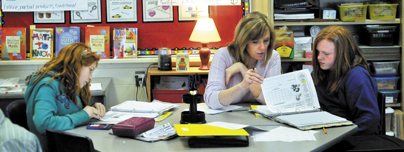 Karen Mayo, a fifth-grade teacher at the James H. Bean School in Sidney helps two students Jade Veillaux, 11, right, and Macey Eubank, 10, left. James H. Bean is one school in the area that has implemented a mass customized learning program that integrates up to three grade levels in one classroom.