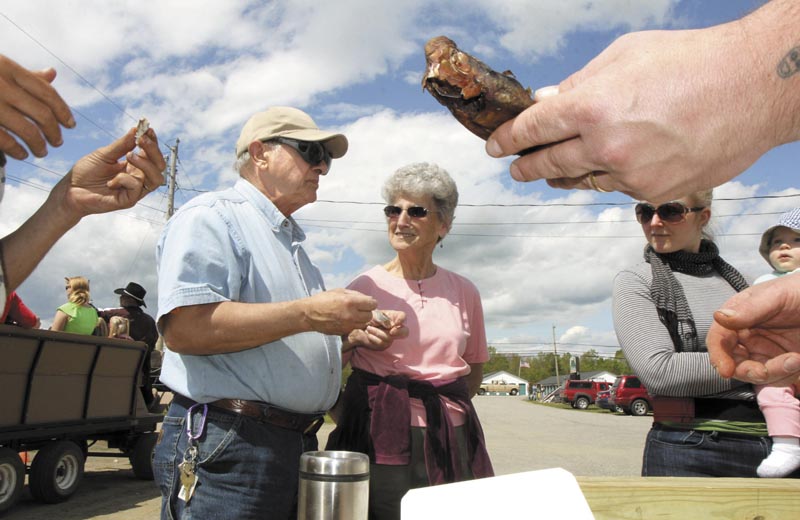 Erma Blakney, of Fairfield, center, looks over as her friend, Edward Fisher, tastes a smoked alewife during the 2nd annual Benton Alewife Festival on Saturday. Rob Hebert, who smoked the fish, said it takes about 12 hours to smoke a small fish and 18 hours to smoke larger ones. Sampling smoked alewives was just one of numerous activities held at the festival, which ended with a floating bonfire on the Sebasticook River Saturday evening.