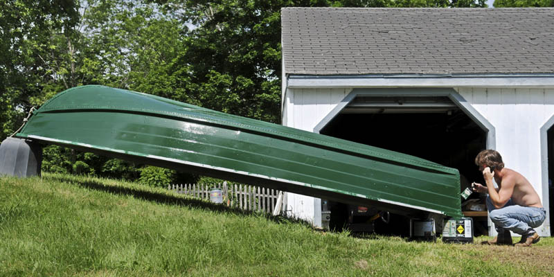 Micah Moore of Rhode Island paints the hull of his family's aluminum boat Sunday outside their summer home on Mill Pond in Wayne. Moore and his father, Brian, plan to cruise up to Pocasset Lake to visit their extended family.