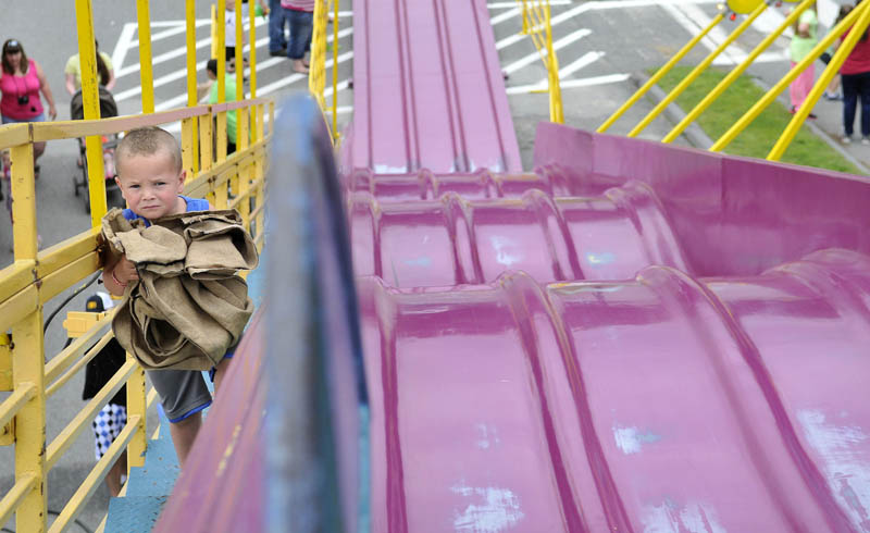 Rashad "Junior" Perkins, 3, clutches a burlap sack sled as he climbs the many steps of the tall slide at the Water Street carnival, during the Fairfield Days Community Festival on Saturday.