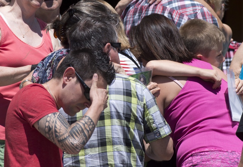 People react as church bells chime 50 times for the victims of the July 6 train crash and blaze in Lac-Megantic, Quebec, Canada, on Saturday. Residents have filed a class-action lawsuit against the railroad.