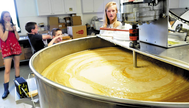 Sophie Lindsay explains the process of preparing a huge container of honey for packaging at Swan's Honey in Albion during Maine Open Farm Day on Sunday, as from left, an unidentified girl, Alex Smith, and his brother, Ben, sample honey-topped ice cream. Farms statewide opened up their operations Sunday to visitors to learn about agriculture.