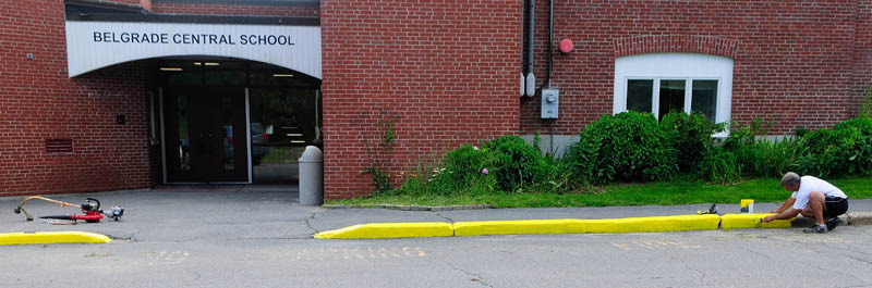 Building caretaker Dan Wilson paints the curb in front of Belgrade Central School on Friday as the school prepares for the return of students in Belgrade.